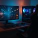 Modern gaming setup with dual monitors, ergonomic chair, LED lighting, and surround sound